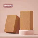Two cork yoga blocks on a pink platform with a pink background