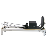 Pilates reformer machine with black carriage and footbar on white frame for fitness workouts