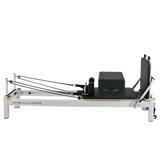 Pilates reformer machine with black carriage and footbar on white frame for fitness workouts