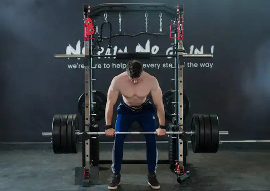 Man lifting heavy barbell on a smith machine during deadlift exercise in a gym setting.