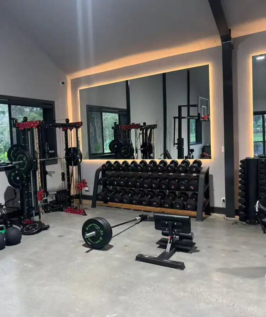 Home gym with dumbbells, barbell, bench, and rack showing the best gym equipment for full-body workouts at home.