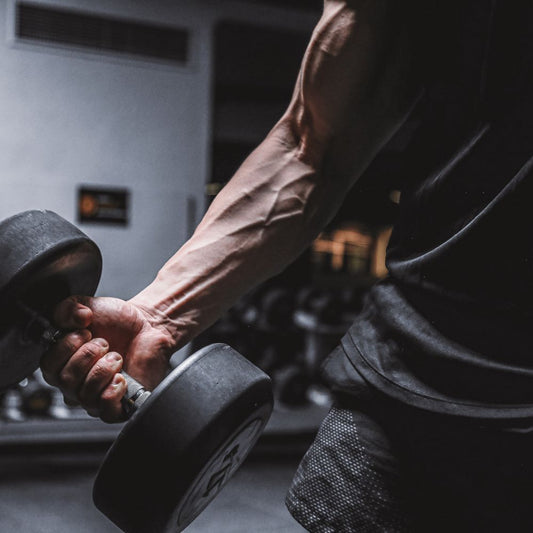 man lifting a heavy hex dumbbell, highlighting arm muscles and grip strength during workout