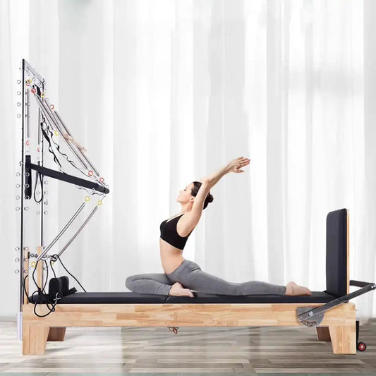 Woman performing stretching exercise on a wooden pilates reformer machine