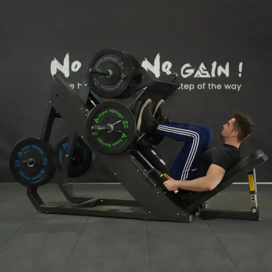 Man performing leg press exercise on a leg press machine loaded with weight plates in a gym.