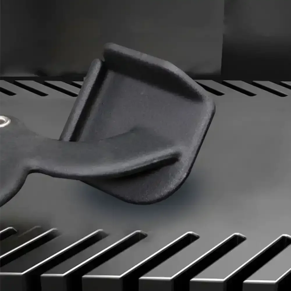 Black plastic scraper tool resting on a dark metal grill surface