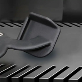 Black plastic scraper tool resting on a dark metal grill surface